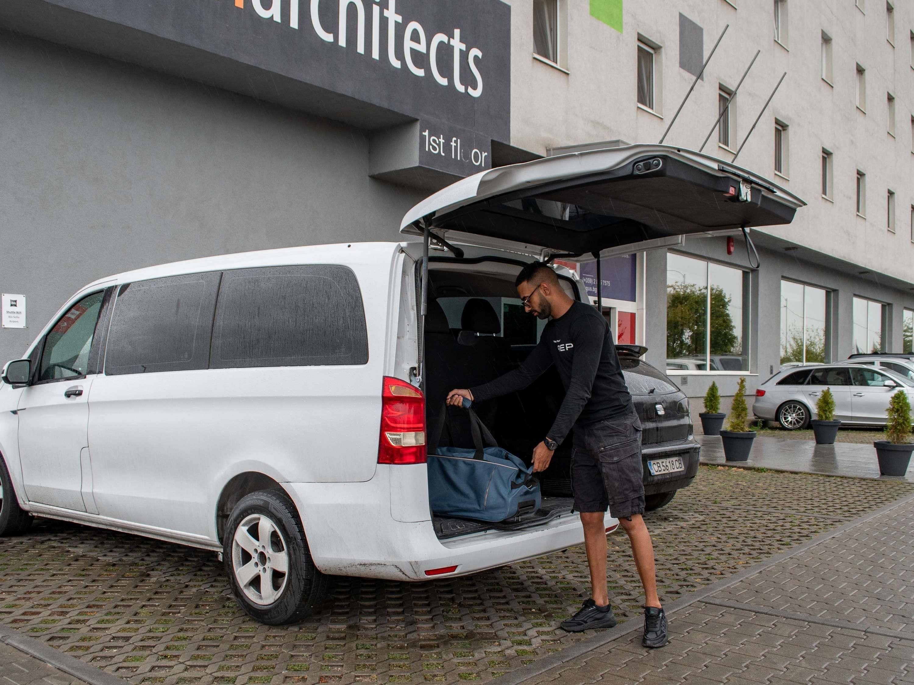 A white van parked in front of a building with a sign that reads 'architects'.