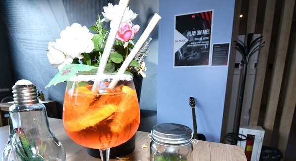 A cocktail with a flower garnish and a straw, a salt shaker, and a jar on a table.