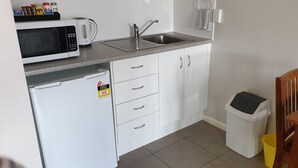 Cozinha compacta com micro-ondas, pia e armários.