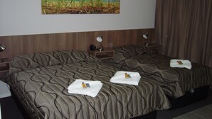Quarto de hotel com uma cama grande, duas mesas de cabeceira e um quadro na parede.