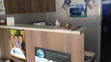 A reception desk with a wooden finish, a small statue, and several informational posters.