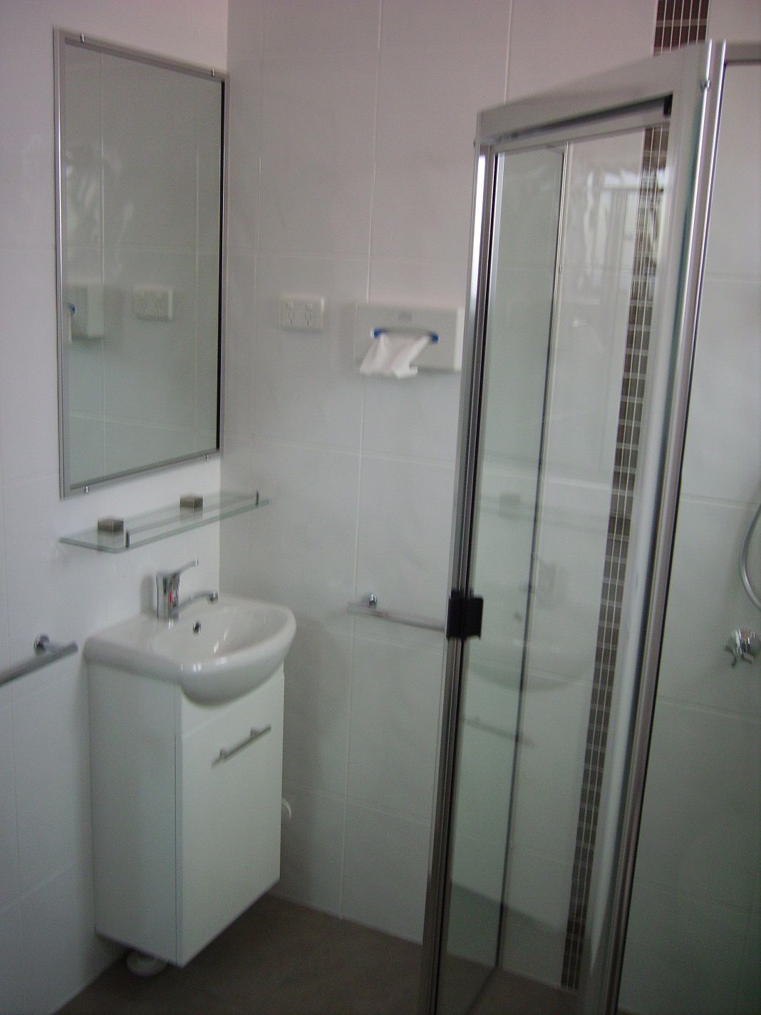 Une salle de bain avec une douche à parois de verre, un lavabo et un miroir.