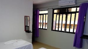 A hotel room with two beds, a window with bars, a mirror, and purple curtains. - Pousada Damasco (Brasília)