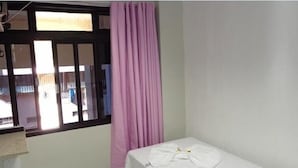 A small, single-bed room with a window and a curtain. - Pousada Damasco (Brasília)
