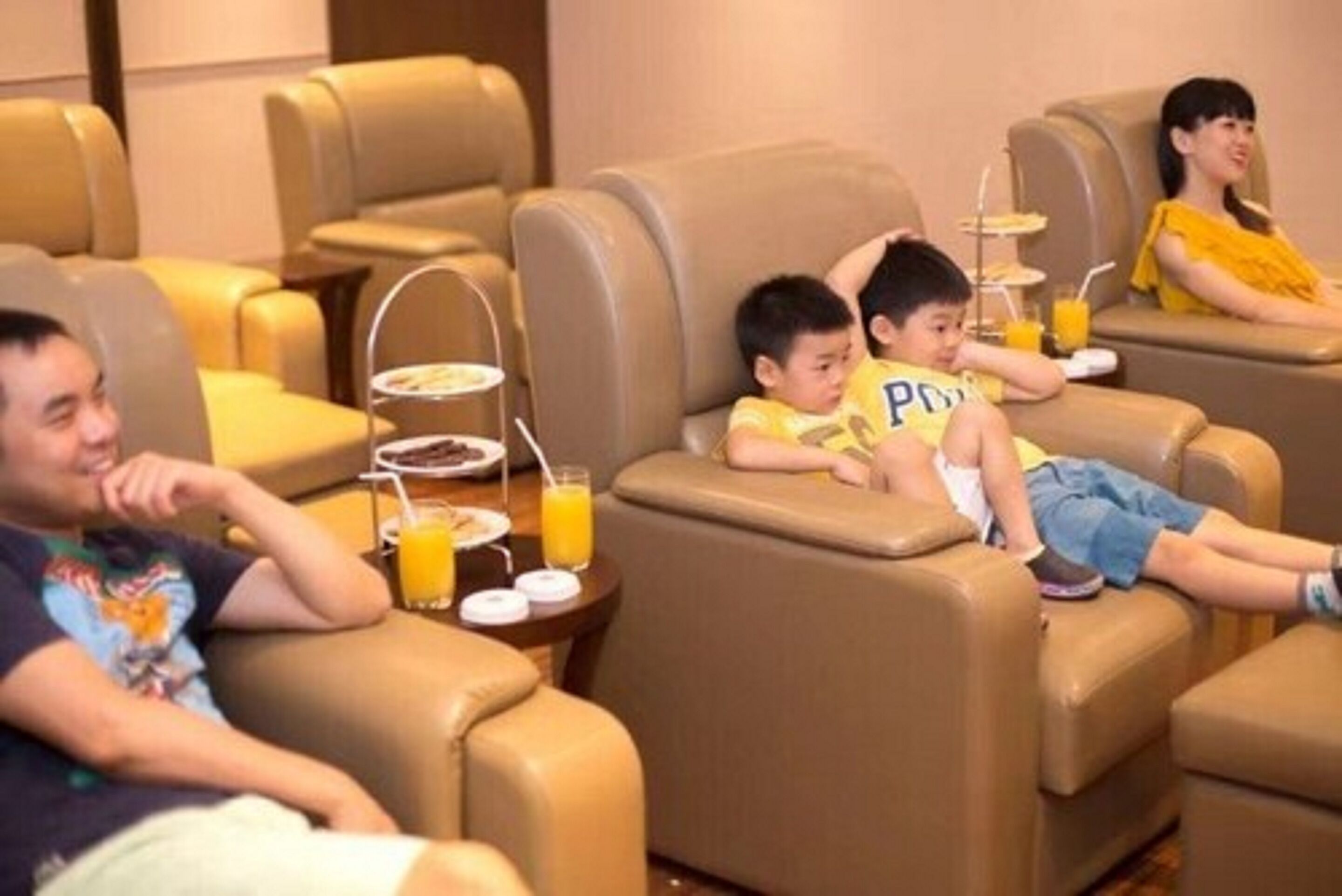 A hotel room with leather reclining chairs, a small table with a tray of breakfast items, and a glass of orange juice.