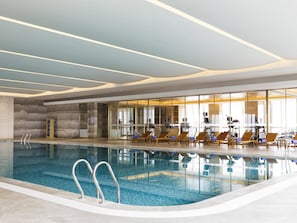 Una piscina techada, sillones reclinables de piscina