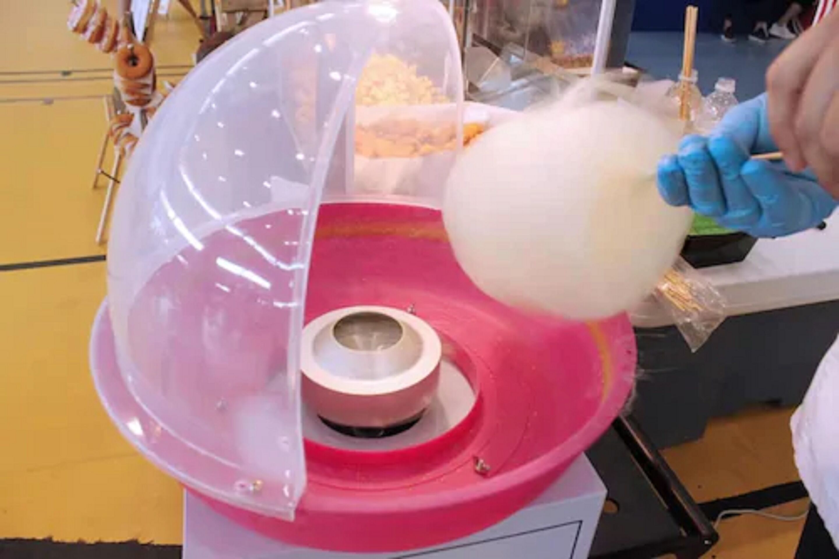 A cotton candy machine with a transparent dome and a pink base.