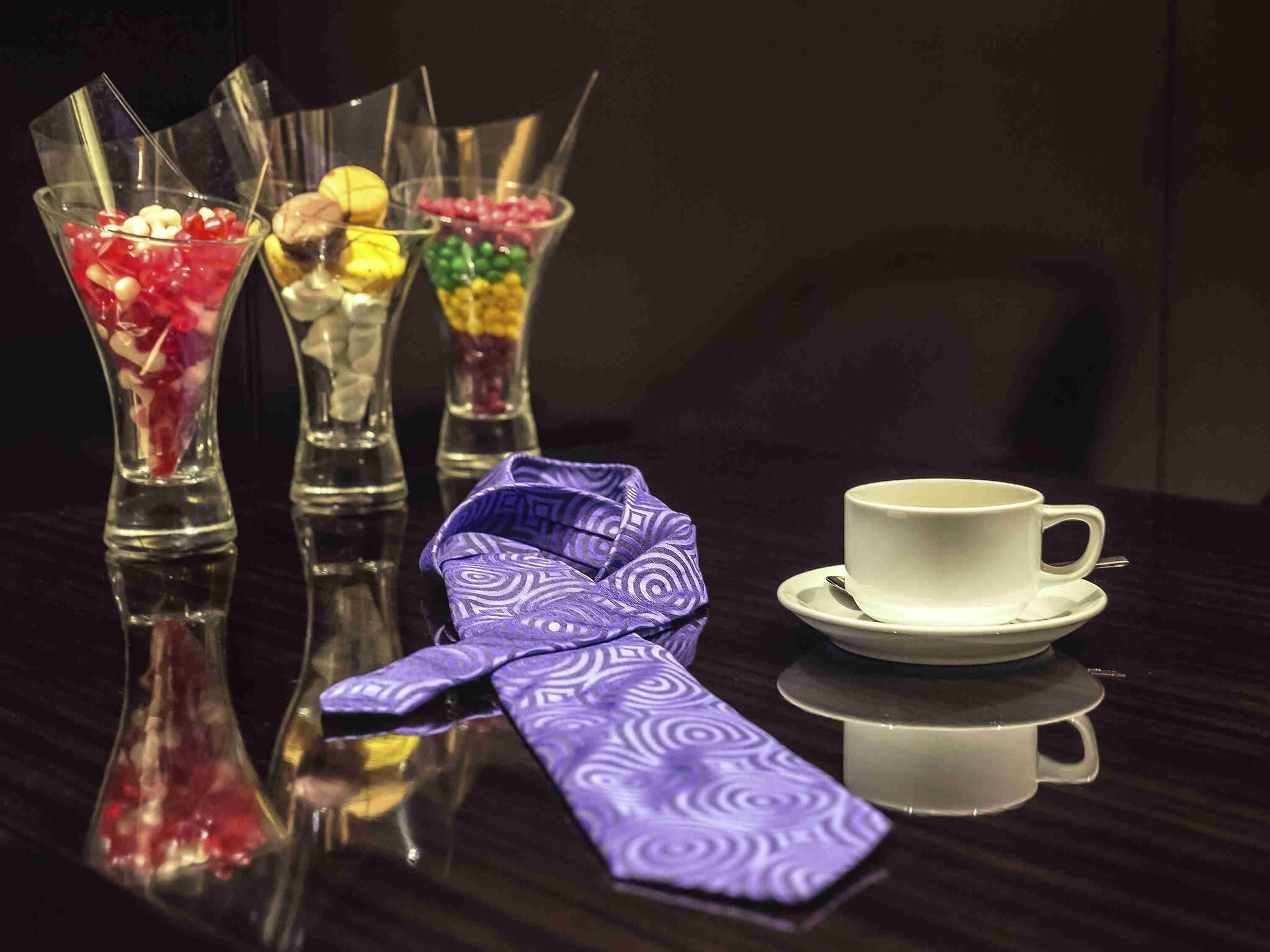 A table with three glass dessert cups, a white cup with a saucer, and a purple patterned napkin.