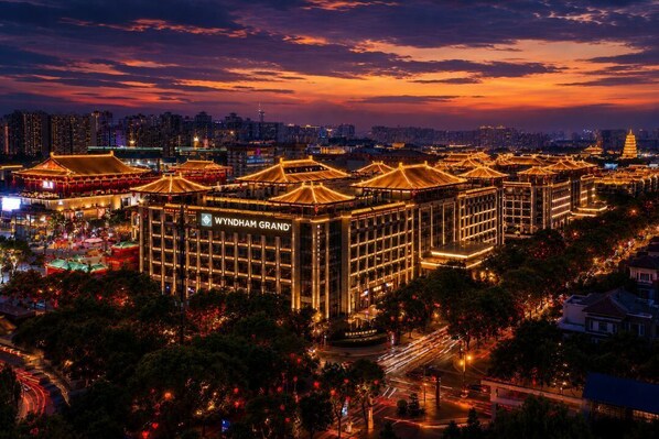A hotel with traditional architecture, a modern building labeled 'YINDHAM GRAND,' and a cityscape in the background. - Wyndham Grand Xian South (Xi'an)