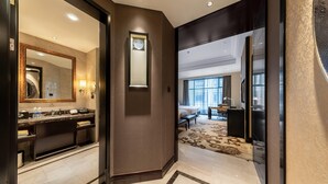 Un hall d’hôtel moderne avec un sol en marbre, un grand miroir, un comptoir d’accueil et une vue sur une partie de la chambre.