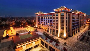 Un hôtel moderne doté d’une architecture de style traditionnel, comprenant plusieurs étages, une cour intérieure aménagée avec des sièges et une façade bien éclairée.