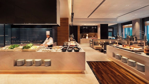 Un buffet moderne, proposant une grande variété de plats, avec un chef cuisinier qui prépare les aliments en arrière-plan.
