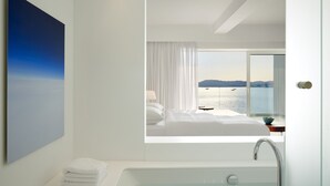 A modern hotel room with a large window offering a view of the sea and mountains. - Nikki Beach Resort & Spa Porto Heli (Ermionida)