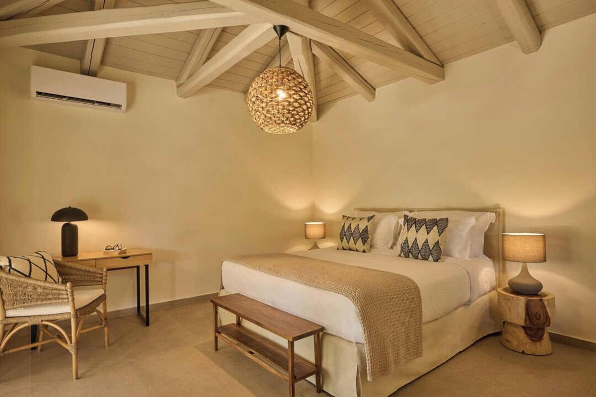Ein Schlafzimmer mit Bett, Nachttischen, einem Schreibtisch, einem Stuhl und einer Pendelleuchte.