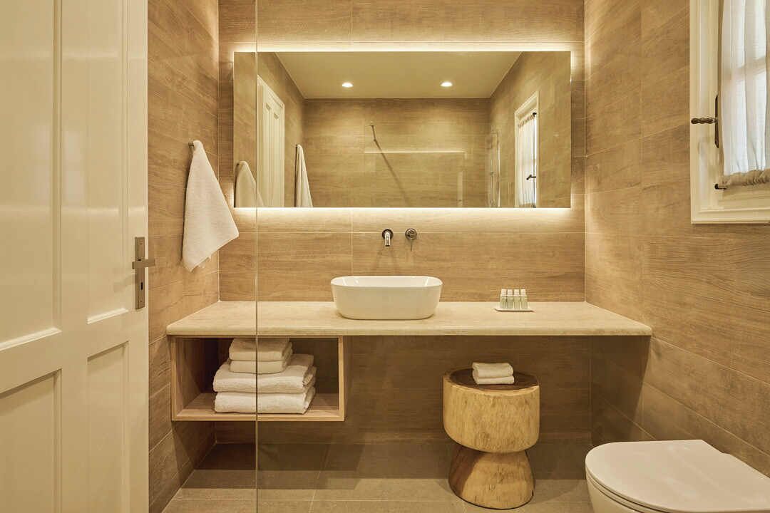 A modern bathroom with a large mirror, a sink, a toilet, and a towel rack.