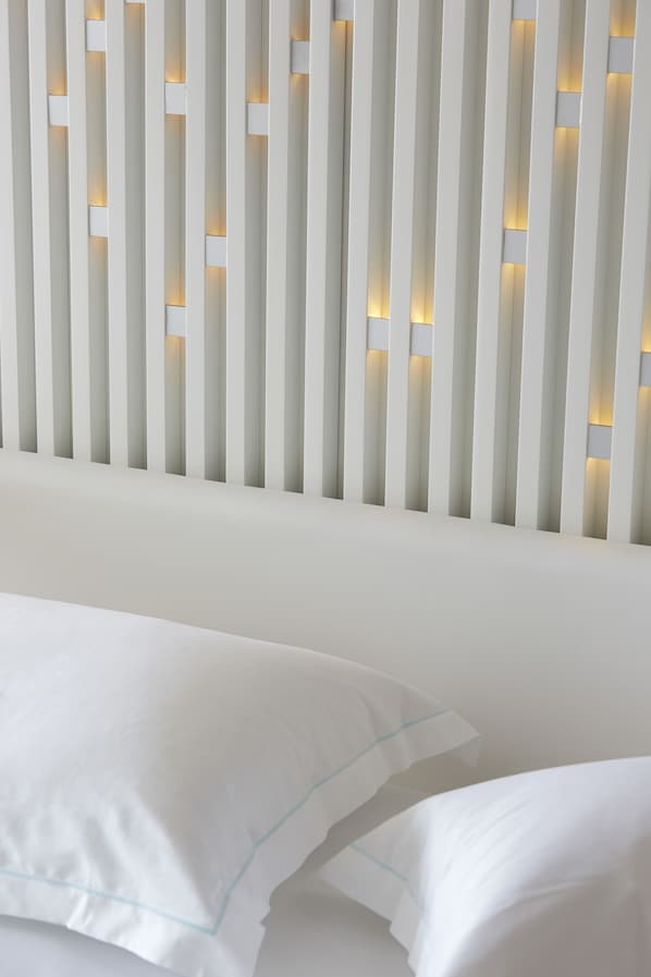 A modern room with a white headboard featuring vertical slats and integrated lighting.