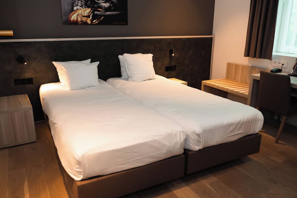A modern hotel room with a large bed, bedside tables, a desk, and a chair.