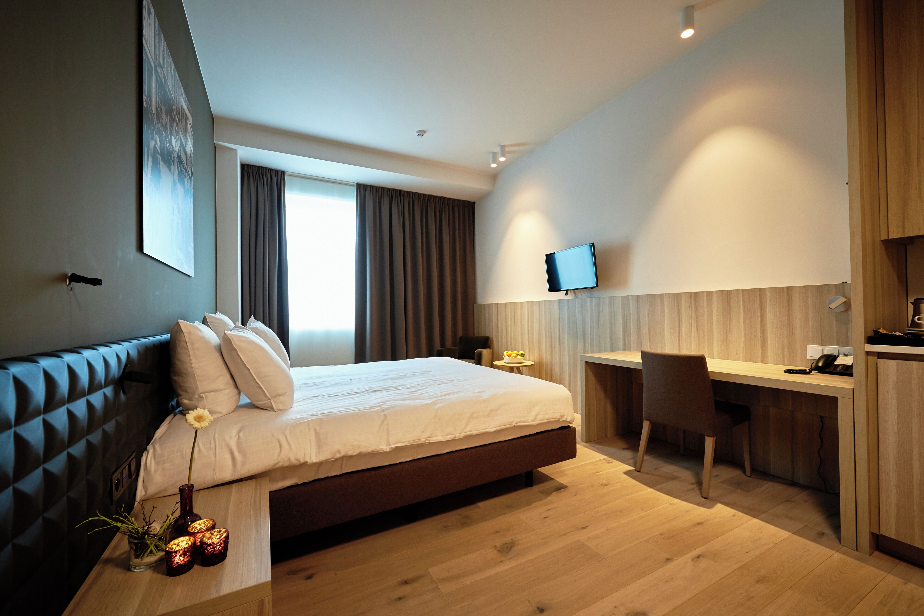 A modern hotel room with a large bed, a desk, and a television.