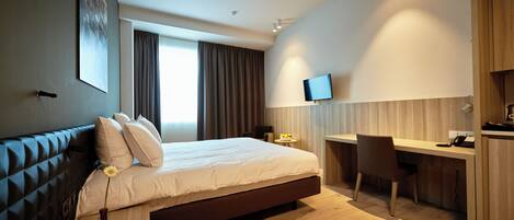 Una habitación de hotel moderna con una cama grande, un escritorio y una televisión.