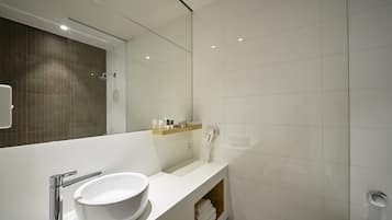 A modern bathroom with a white sink, a mirror, a glass shower enclosure, and a towel rack.