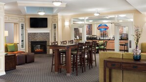 A spacious living area with a fireplace, a dining table with chairs, and a television mounted on the wall. - Baymont by Wyndham Odessa (Odessa)