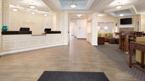 A hotel lobby with a reception desk, seating area, and a television mounted on the wall. - Baymont by Wyndham Odessa (Odessa)