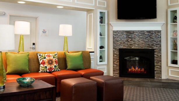 A modern living room with a sectional sofa, a fireplace, and a mounted TV. - Baymont by Wyndham Odessa (Odessa)