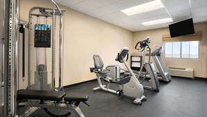 A gym with exercise equipment, a bench, and a TV on the wall. - Baymont by Wyndham Odessa (Odessa)