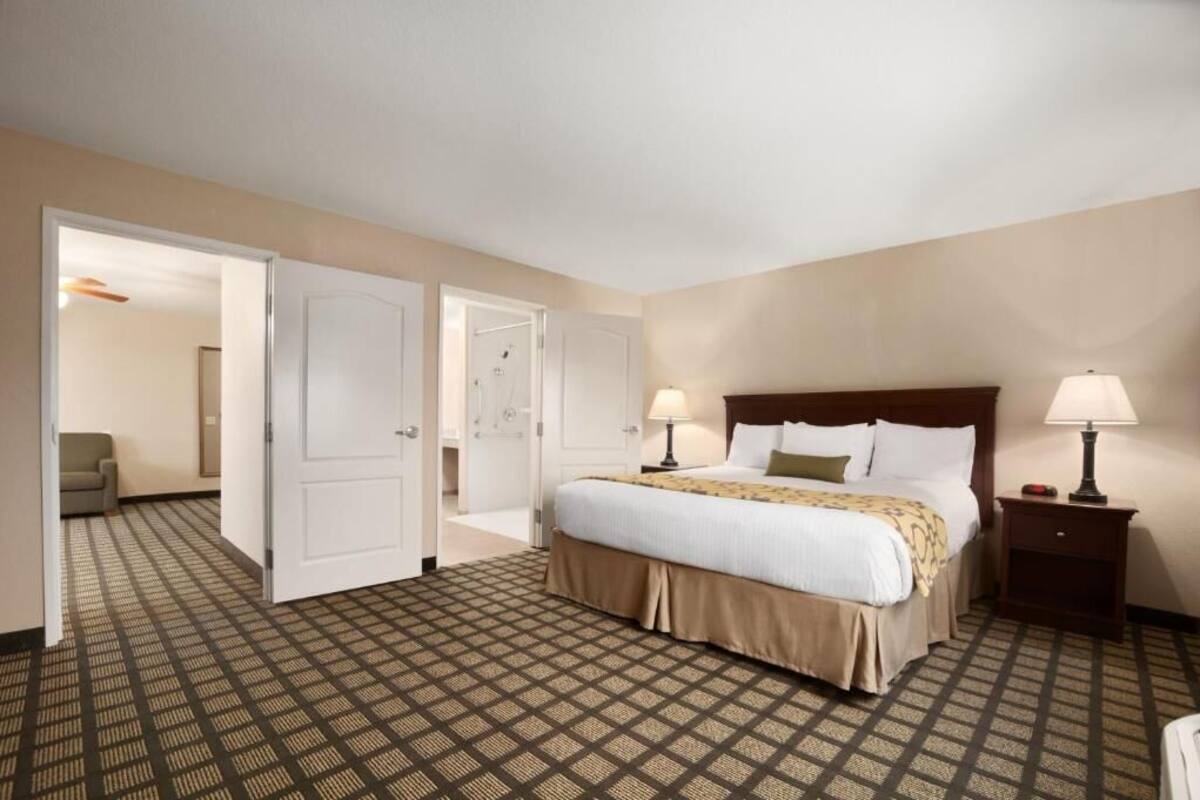 Een hotelkamer met een groot bed, twee bedlampen, een nachtkastje en een kamerbreed tapijt met dessin.