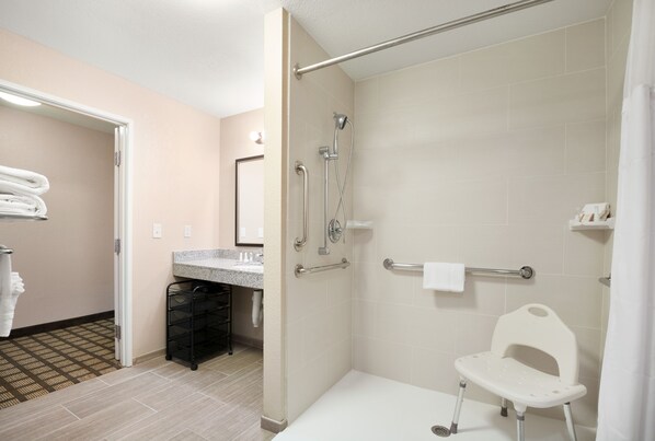 Un baño moderno con ducha, inodoro y lavamanos. Hay un perchero y un estante pequeño.