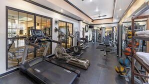Une salle de sport équipée de tapis de course, de vélos elliptiques et de divers appareils de musculation.