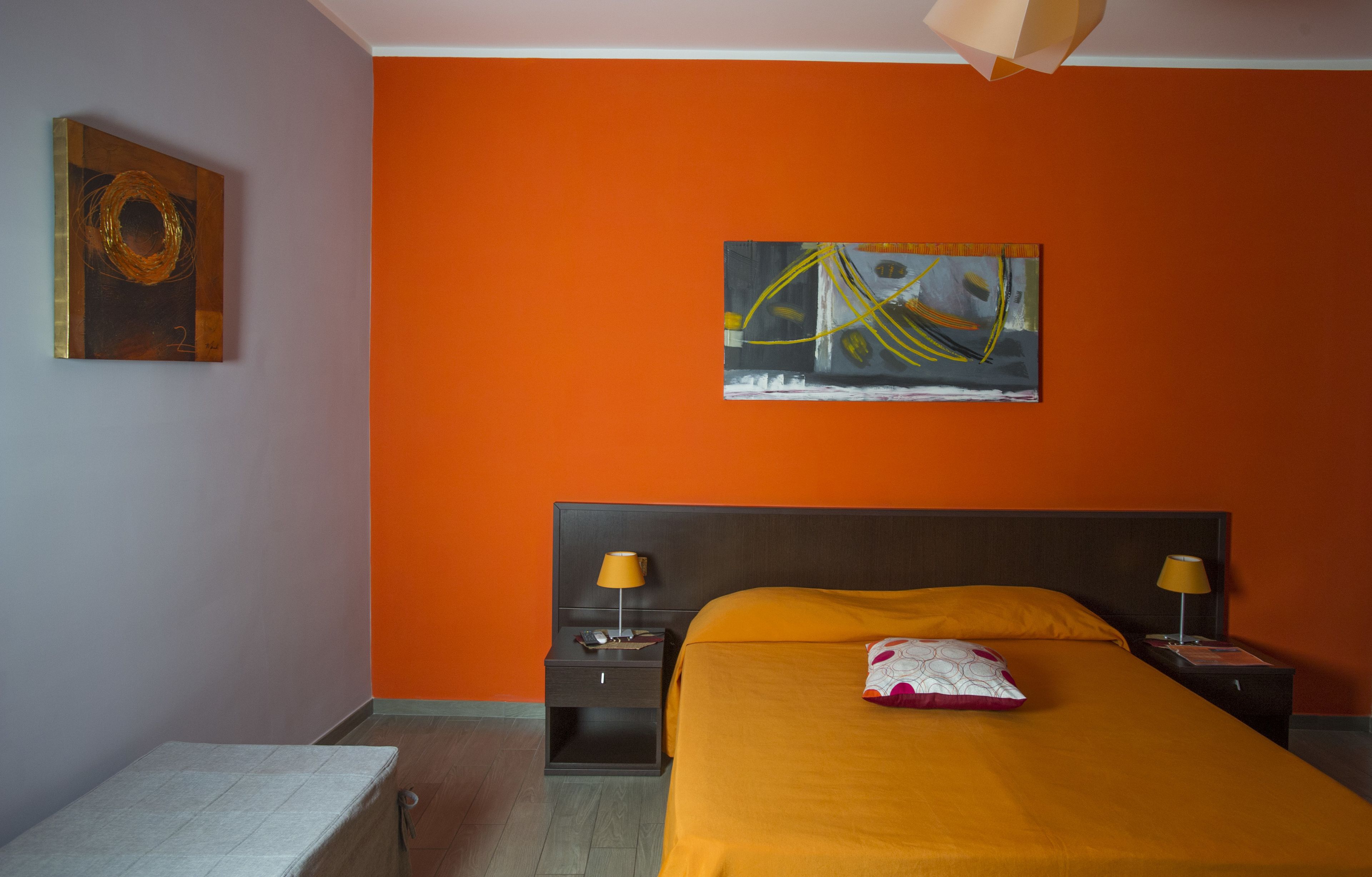 A hotel room with a large bed, two bedside tables with lamps, a nightstand, and a painting on the wall.