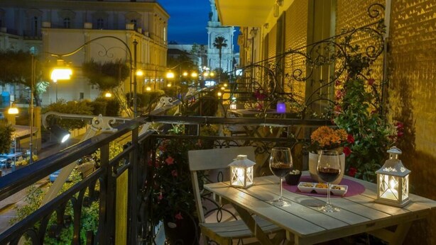 A balcony with a table set for dining, a lantern, and a wine glass. - B&B Eco (Pompei)