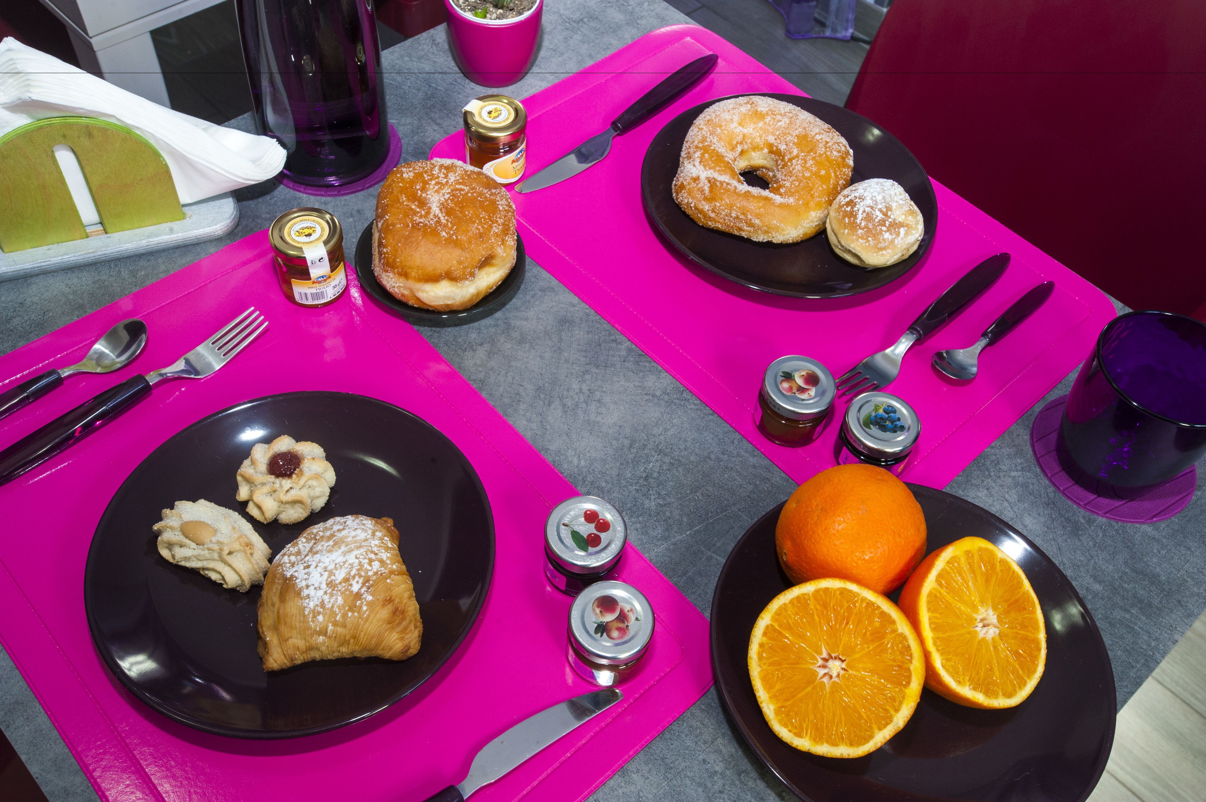 A table with plates of pastries, a knife, a fork, and a spoon.