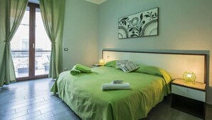 A bedroom with a green bed, a nightstand with a lamp, a window with curtains, and a wall art piece. - B&B Eco (Pompei)