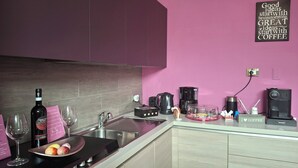 A modern kitchen with a pink wall, stainless steel appliances, and a coffee station. - B&B Eco (Pompei)