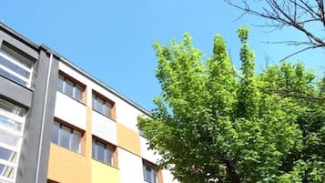 Un edificio de varios pisos con un estilo arquitectónico moderno, que presenta una combinación de paneles de fachada blancos y naranjas y ventanas amplias.