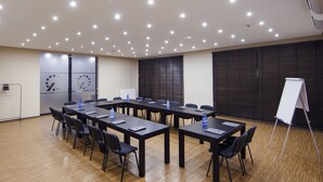 Una sala de conferències amb una taula llarga, cadires, una pissarra i un dispensador d'aigua.