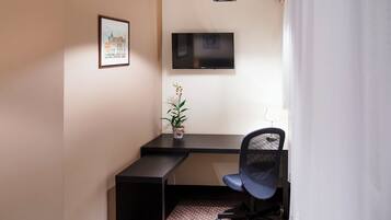 Een kleine kantoorruimte met een bureau, stoel en een wandgemonteerde flatscreen televisie.