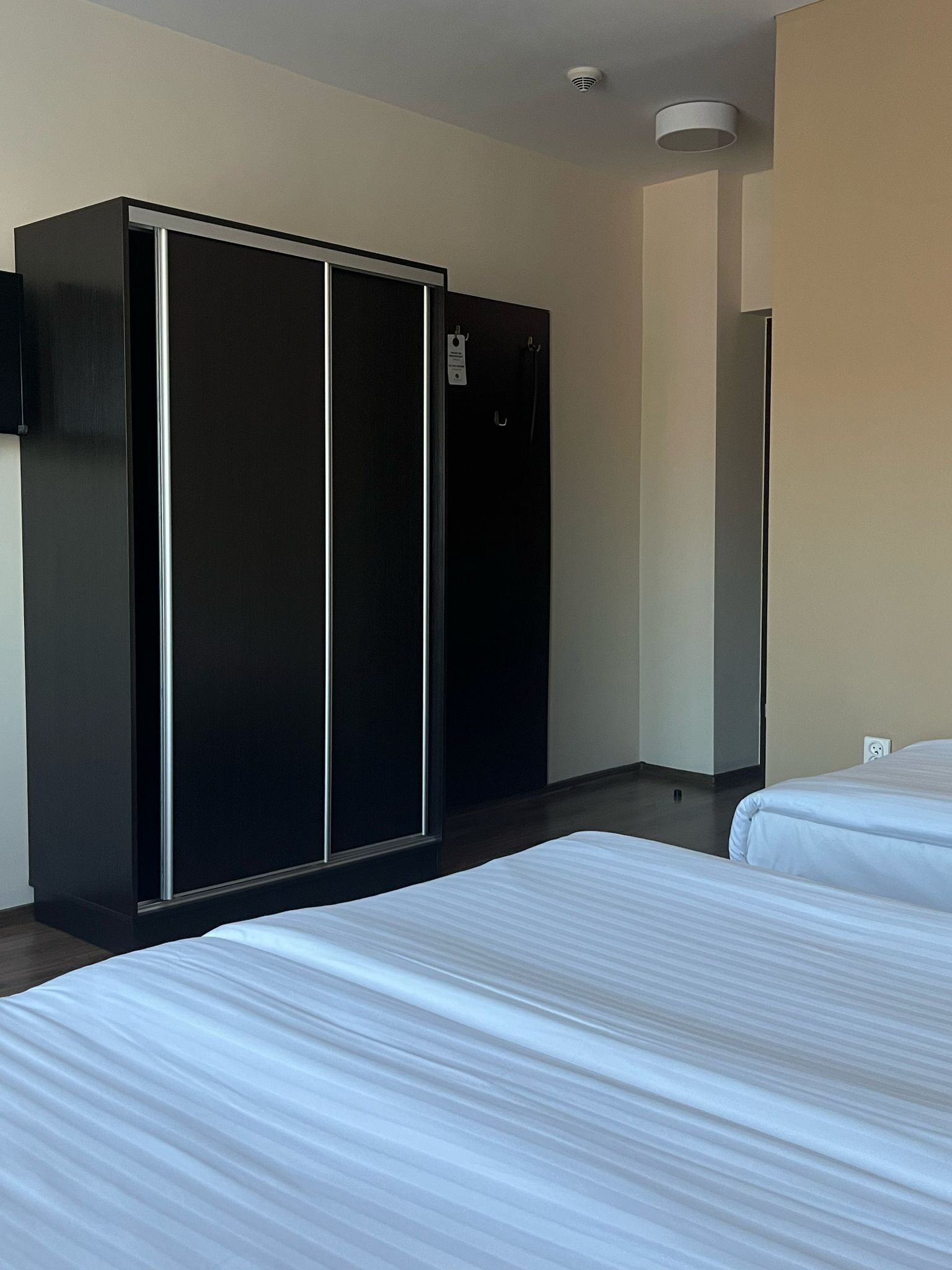 Habitación de hotel con un armario grande, dos camas y un espejo.