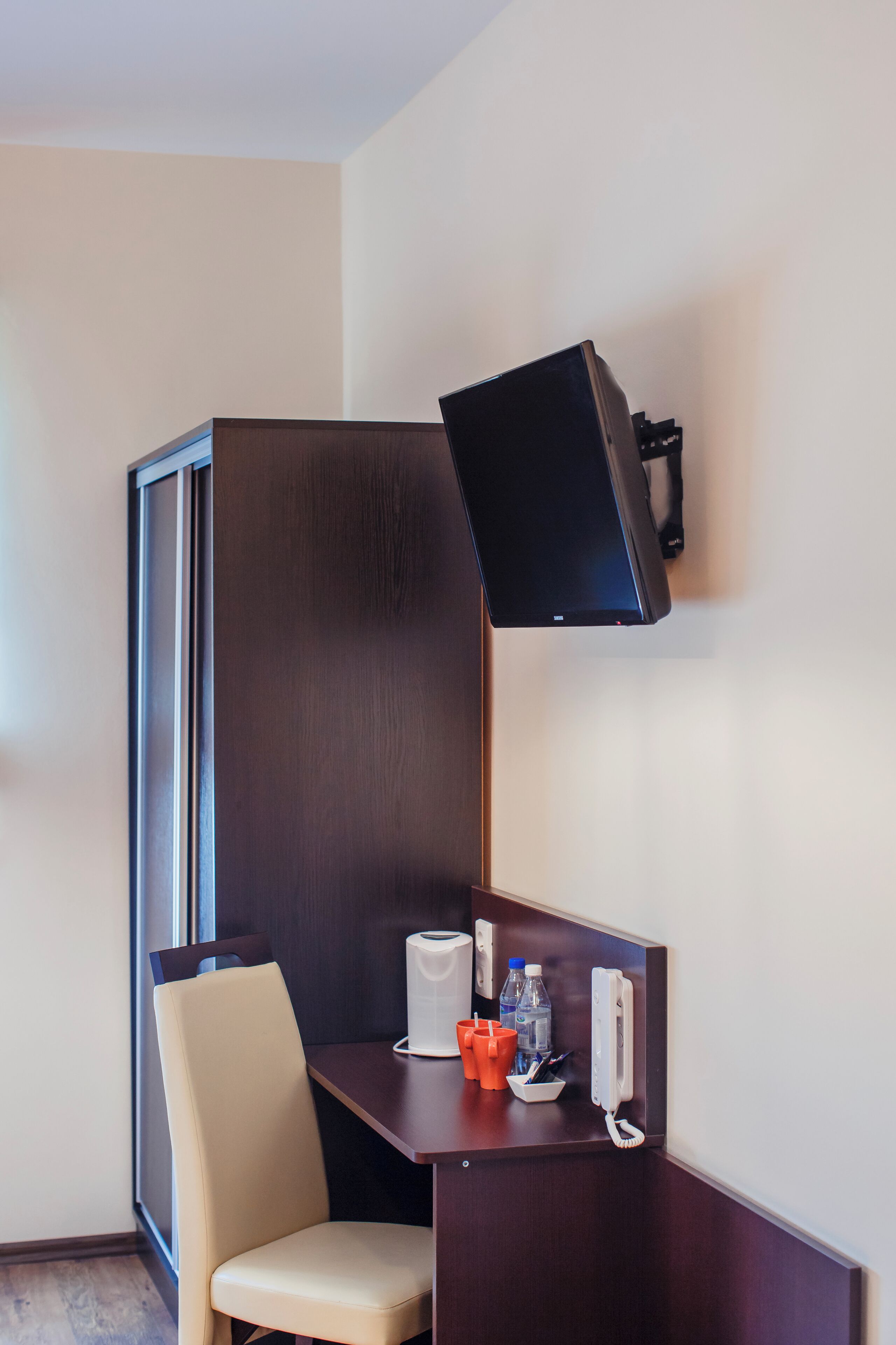 Habitación de hotel con escritorio, silla y televisor montado.