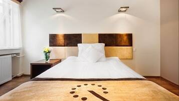 A hotel room with a bed, a nightstand, and a wall-mounted light fixture.