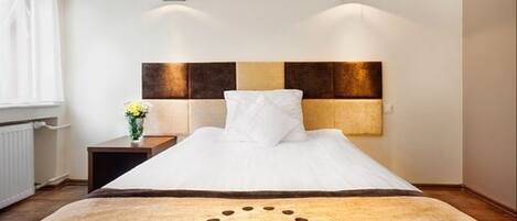 A hotel room with a bed, a nightstand, and a wall-mounted light fixture.
