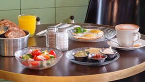 Une table de petit-déjeuner avec une variété d’aliments, une tasse de café et une sélection de bouteilles de vin disposées sur des étagères à l’arrière.
