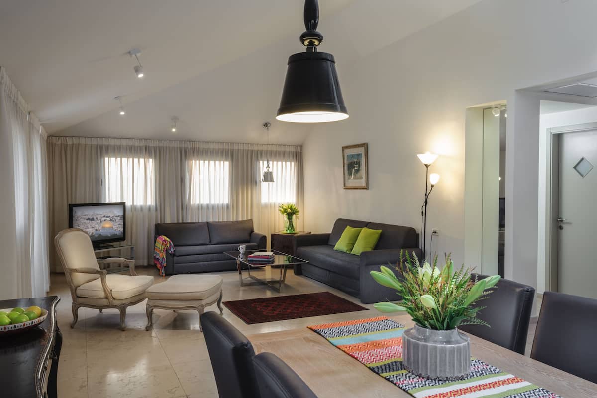 Een moderne woonkamer met een bank, fauteuils, een salontafel en een eettafel met stoelen.