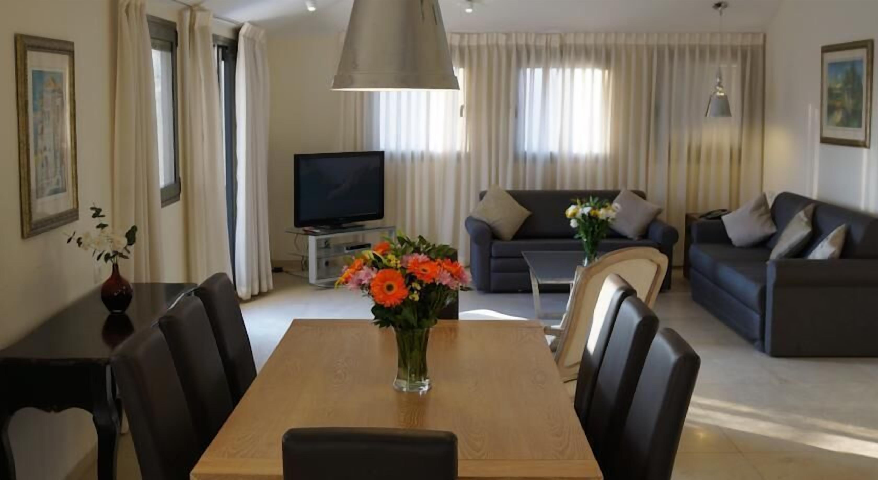 A modern living room with a dining table, sofas, and a TV.