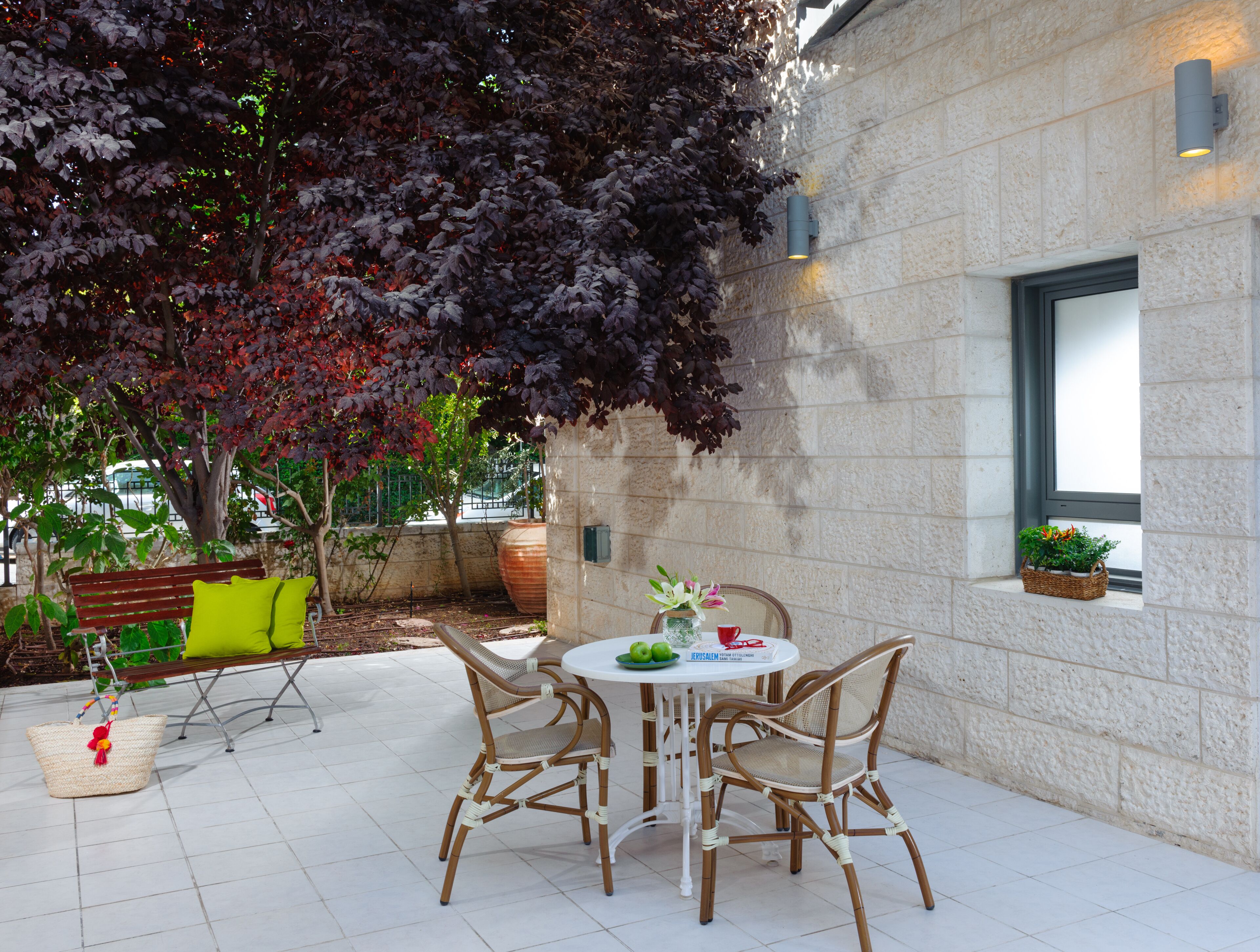 Eine Terrasse im Freien mit einem runden Tisch, Korbstühlen und einer Bank.