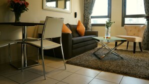 Un salon avec un canapé, deux fauteuils, une table basse et un vase de fleurs.