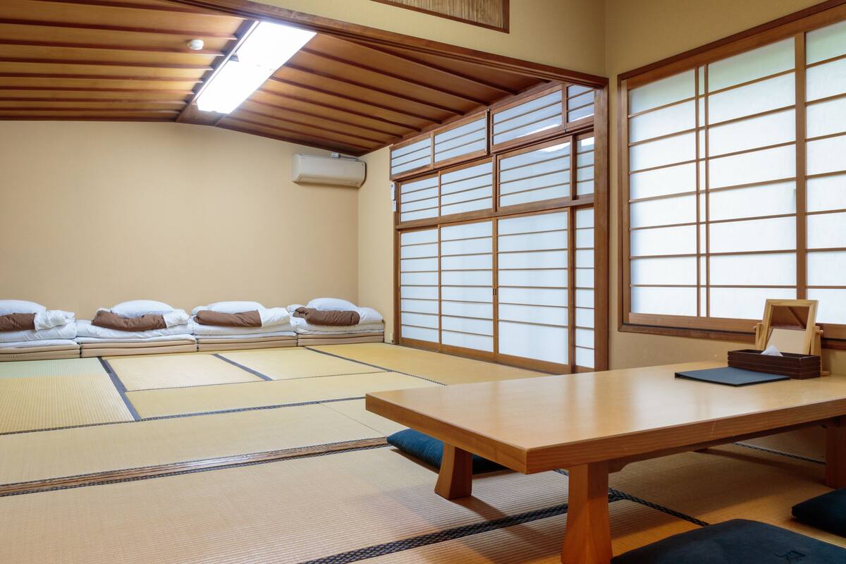 A traditional Japanese room with tatami mats, a low wooden table, and futon beds.