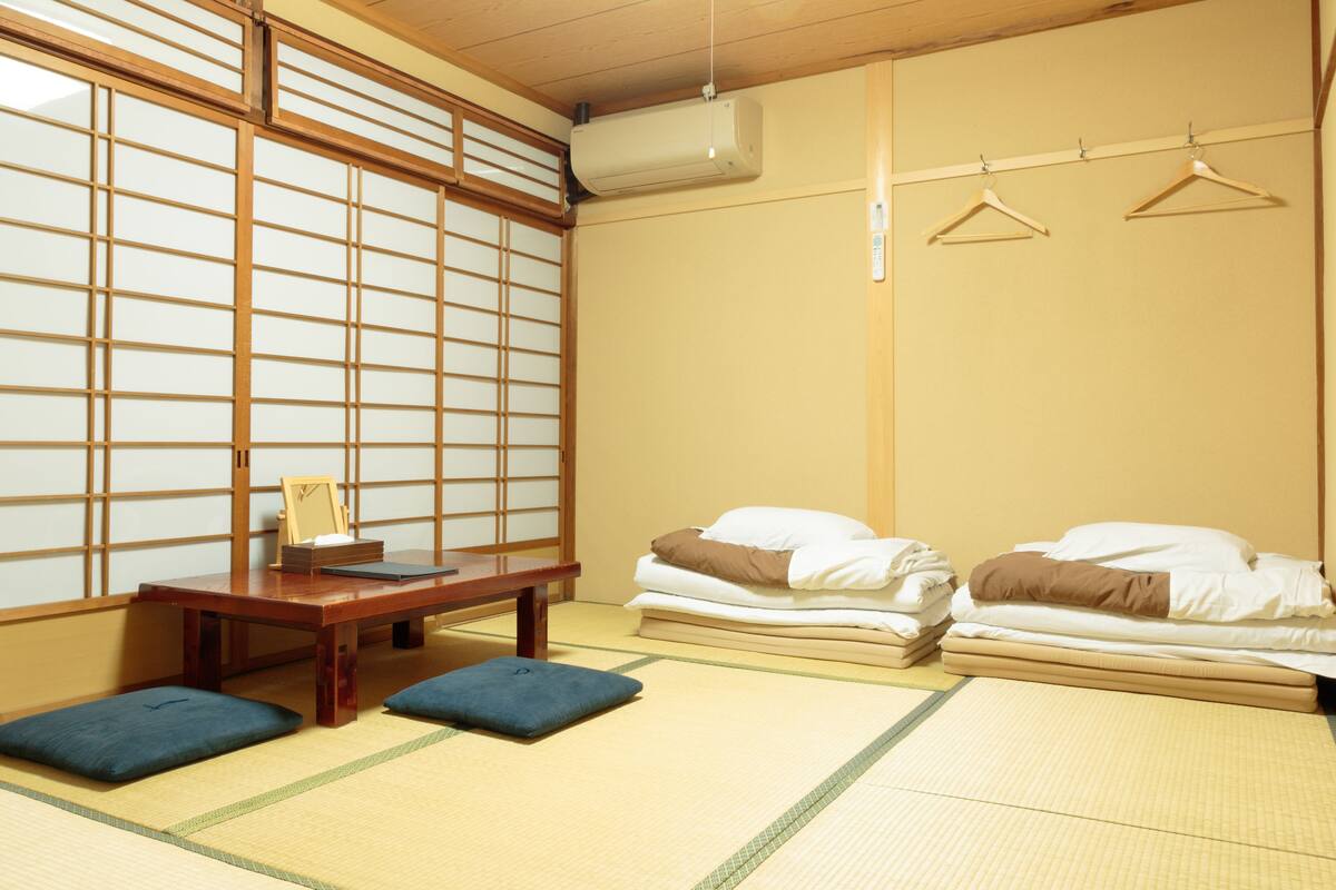 A traditional Japanese room with tatami flooring, a low wooden table, and a futon bed.